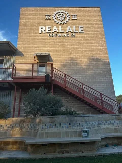The Real Ale Brewing Co. building and taproom stairs under a bright Blanco sky