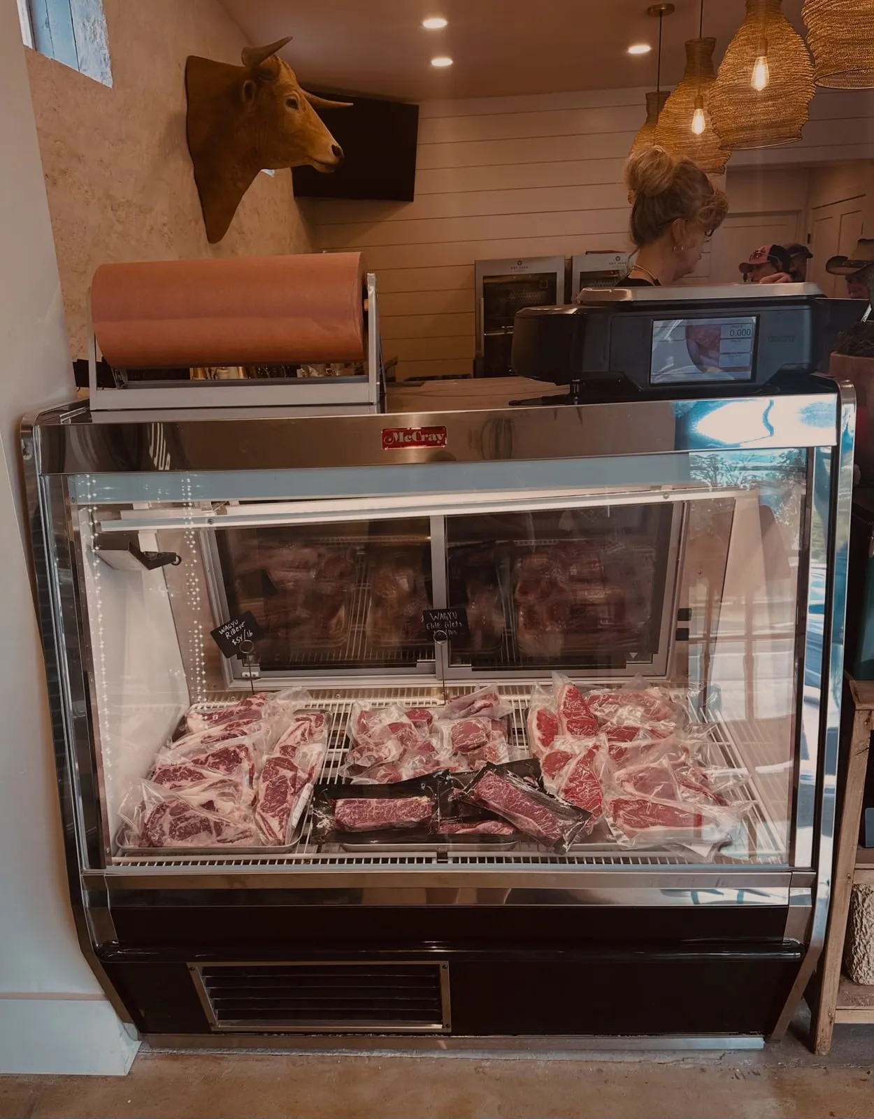 The meat counter at The Local Bull, Wagyu steaks and ground beef in the case, longhorn mount over the register