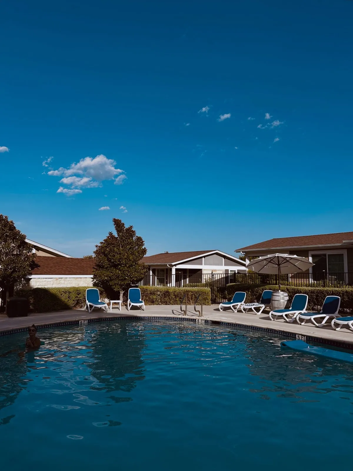 The pool at Carter Creek on a cloudless afternoon, loungers along the deck and vineyard villas behind