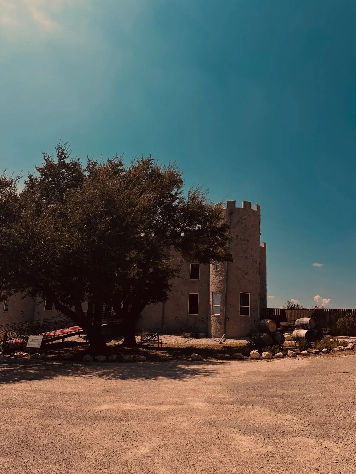 The stone castle itself under a live oak, gravel drive out front